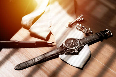 Closeup at luxury men wristwatch with black dial and leather strap. Men wristwatch on the wooden desktop.の写真素材