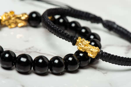 Wealth PiXiu bracelet, closeup at the gold PiXiu. PiXiu is a Chinese mythical auspicious creature, also known as PiYao.の写真素材
