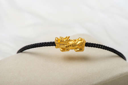 Wealth PiXiu bracelet, closeup at the gold PiXiu. PiXiu is a Chinese mythical auspicious creature, also known as PiYao.の写真素材