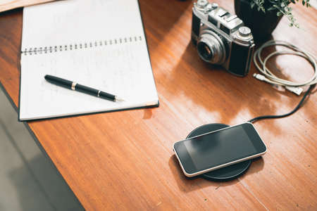 Charging the smartphone with wireless charger on desktop.