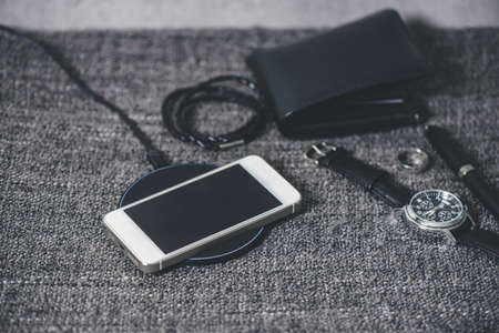 Charging the smartphone with wireless charger on gray cloth.