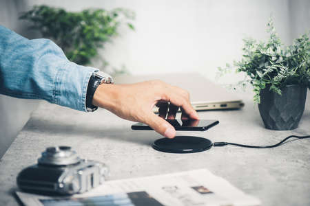 Charging the smartphone with wireless charger on desktop.の写真素材