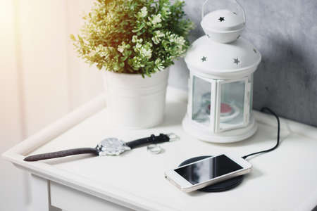 Charging the smartphone with wireless charger on the white desk.