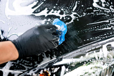 Washing the black car. Car cleaning and car care concept.