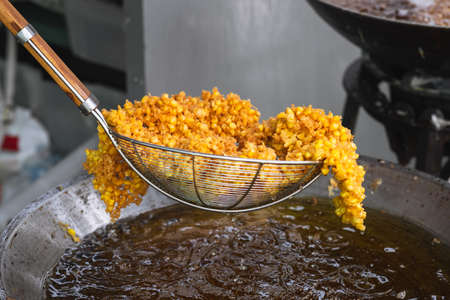 Frying corn in hot oil. Cooking crispy deep fried corn, vegetarian food.の写真素材