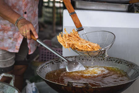 Frying shredded taro in hot oil. Cooking crispy shredded taro, vegetarian food.の写真素材