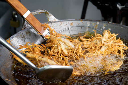 Frying shredded taro in hot oil. Cooking crispy shredded taro, vegetarian food.の写真素材