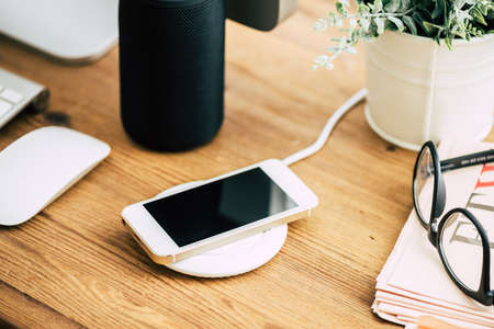 Charging the smartphone with wireless charger on desktop.