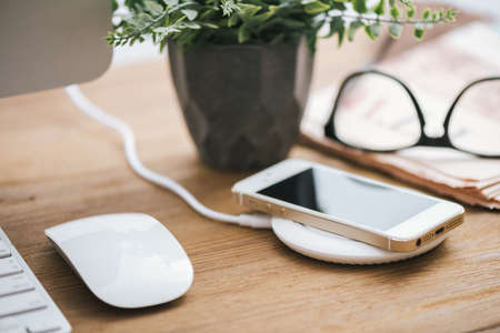 Charging the smartphone with wireless charger on desktop.の写真素材