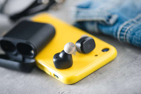 Pair of black true wireless earbuds with smartphone. Relaxation concept.の写真素材