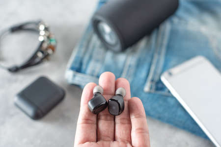 Pair of black true wireless earbuds with smartphone. Relaxation concept.