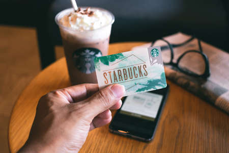 CHONBURI, THAILAND - JANUARY 23, 2020: Starbucks card with a cup of Iced Signature Chocolate in the background. Starbucks is the world's largest coffee house with over 20,000 stores in 61 countries.のeditorial素材