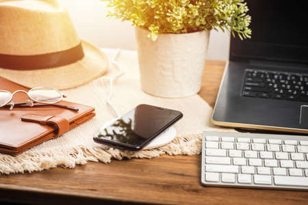 Charging the smartphone with wireless charger on wooden desk. Modern lifestyle concept.