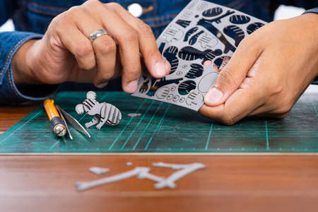 Assembling small cardboard model, the small cardboard parts are made with laser cutting technology....