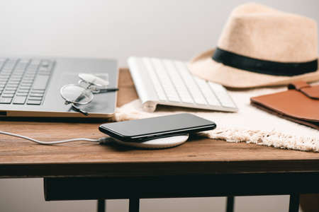 Charging the smartphone with wireless charger on wooden desk. Modern lifestyle concept.の写真素材