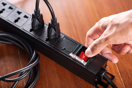 Close up a mans hand turn on the switch on power strip.の写真素材
