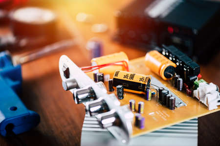 Technician repairing the electronic device. Reparing the audio amplifier. Close up at the orange...