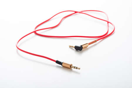 Red AUX(Auxiliary) cable with 3.5 mm jack Male-to-Male isolated over white background. Cable for...