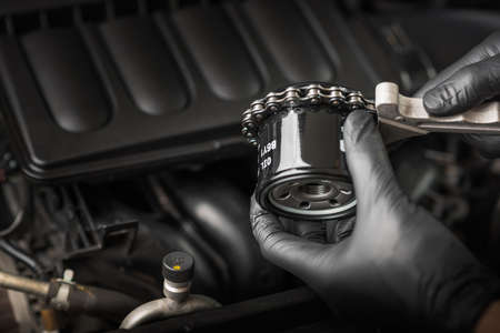 Technician use the chain wrench to change car oil filter. Car maintenance concept.
