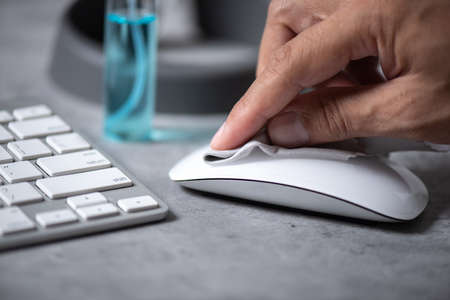 The man cleaning his computer mouse. COVID-19 prevention concept.