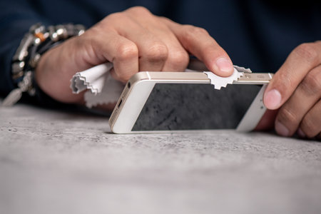 Cleaning the smartphone with soft cloth and alcohol. COVID-19 prevention concept.