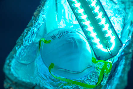 UV light sterilization of face mask to disinfect and reuse. COVID-19 prevention concept.の写真素材