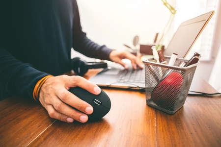 The man using black vertical optical computer mouse with ergonomic design and leave normal computer mouse in the basket.の写真素材