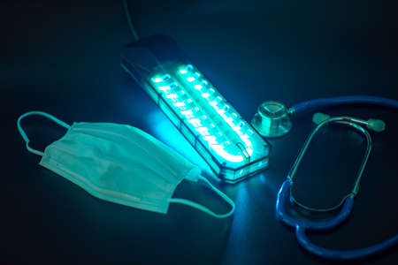 UV light sterilization of face mask to disinfect and reuse. COVID-19 prevention concept.