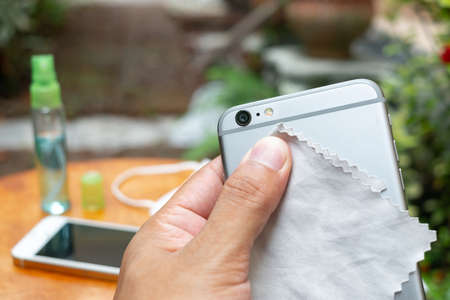 Cleaning the smartphone with soft cloth and alcohol. COVID-19 prevention concept.の写真素材