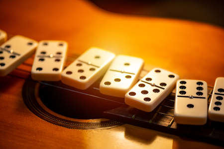 Close up Domino tiles on and old guitar. Dominoes is one of the most famous classic game. Shooting in low light and shallow depth of field.の写真素材