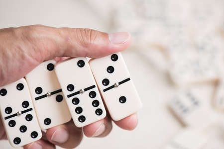 Close up Domino tiles in hand. Dominoes is one of the most famous classic game.