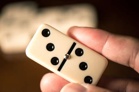 Close up Domino tiles in hand. Dominoes is one of the most famous classic game. Shooting in low...