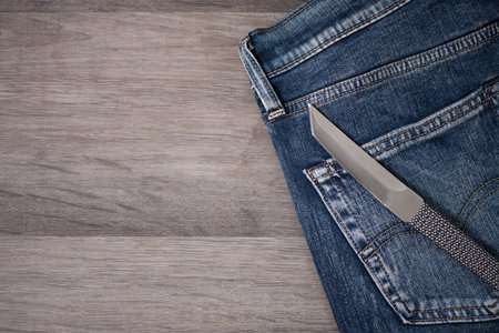 Close up stainless steel pocketknife with Tanto blade on blue jeans. EDC (Every Day Carry) for men.の写真素材