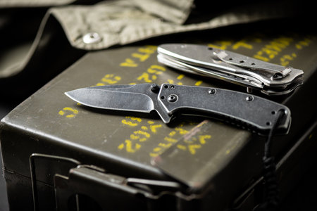 stainless steel pocketknife with military objects in the background.