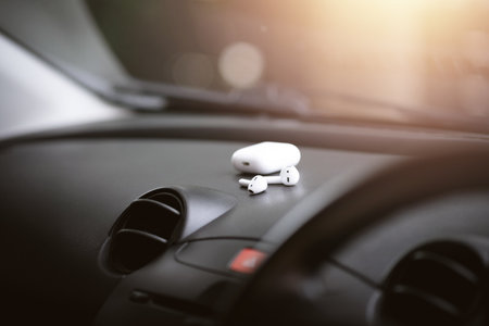 Pair of white wireless earbuds for smartphone on car console.の写真素材