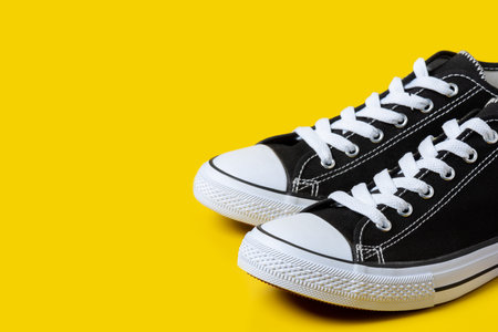 New black and white canvas sneakers isolated over yellow background.の写真素材