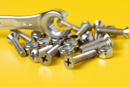 Close up metal screws and nuts over yellow background.の写真素材