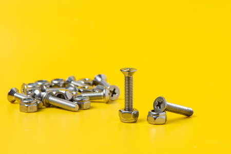 Close up metal screws and nuts over yellow background.の写真素材