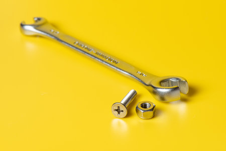 Close up metal screws and nuts over yellow background.の写真素材