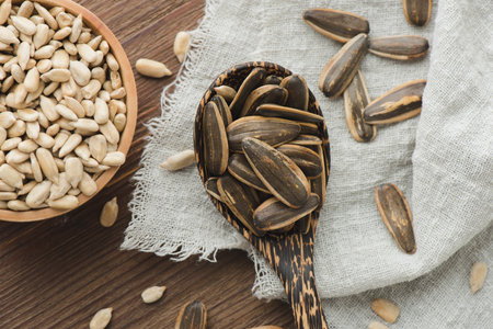 Heap of roasted sunflower seeds with dehulled seeds in the background.の写真素材