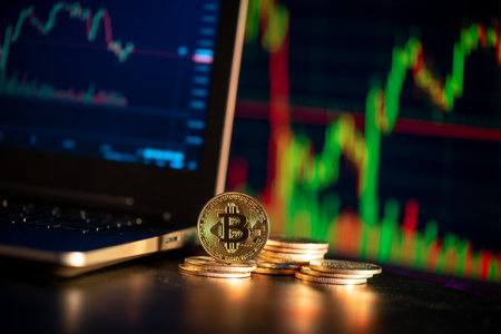 Close up golden coin with bitcoin symbol over stock chart in the background , bitcoin is one of the...