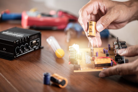 Technician repairing the electronic device. Reparing the audio amplifier. Close up at the orange capacitor.の写真素材