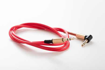 Red AUX(Auxiliary) cable with 3.5 mm jack Male-to-Male isolated over white background. Cable for stereo input and output.の写真素材