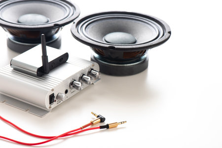 Close up red AUX(Auxiliary) cable with Male jack with amplifier and speakers in the background. Cable for stereo input and output.の写真素材