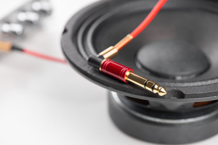 Close up red AUX(Auxiliary) cable with Male jack with speaker in the background. Cable for stereo input and output.の写真素材