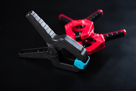 Plastic spring clamp isolated over black background. Equipment for woodworking, carpentry and other handiwork.の写真素材
