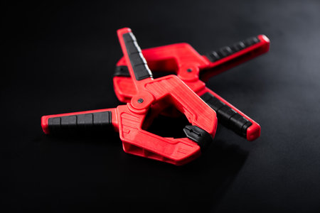 Plastic spring clamp isolated over black background. Equipment for woodworking, carpentry and other handiwork.の写真素材