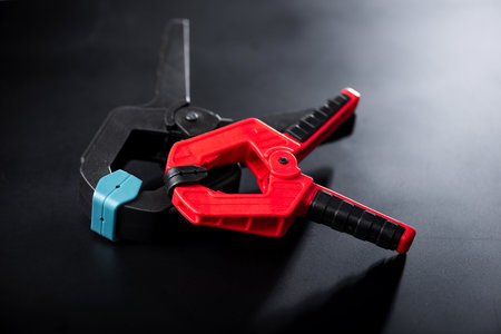 Plastic spring clamp isolated over black background. Equipment for woodworking, carpentry and other handiwork.の写真素材