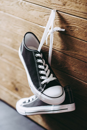 Pair of new black and white canvas sneakers hanging on the wood plank.の写真素材