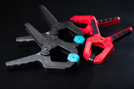Plastic spring clamp isolated over black background. Equipment for woodworking, carpentry and other handiwork.の写真素材